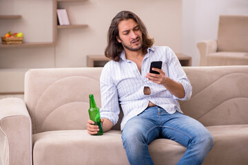 Obraz premium Young man drinking alcohol at home