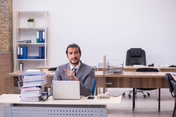 Young male employee unhappy with excessive work in the office