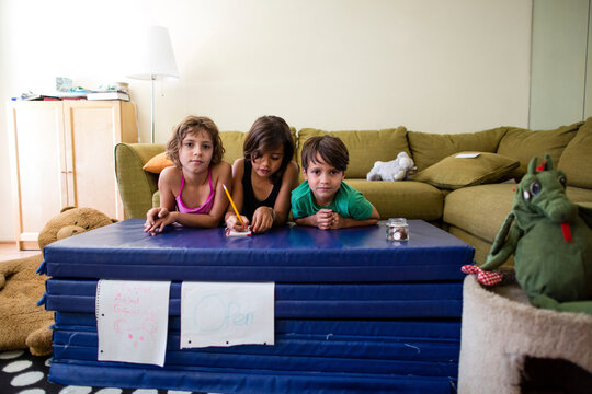 Portrait of siblings leaning on mattress stack at home