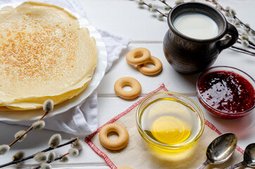 Shrovetide festival. Russian pancakes with raspberry jam, honey and sushki on white wooden background.