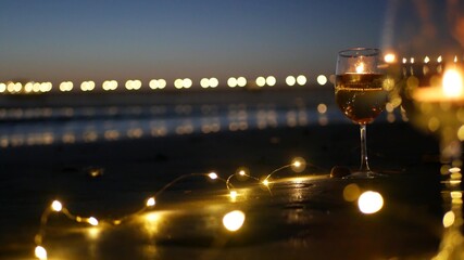 Candle flame lights in glass, romantic beach date, California ocean waves, sea water. Candlelight...