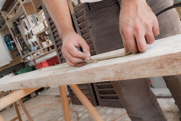 Male carpenter working with wood material in a garage.