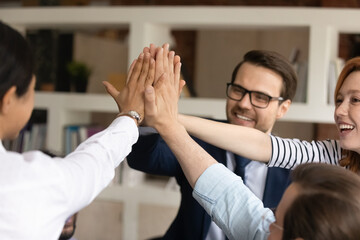 Close up crop of smiling multiracial colleagues coworkers celebrate work success at meeting in...