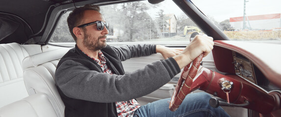 Man in retro clothes driving vintage American car.