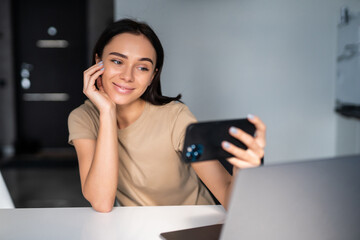 Young woman taking selfie or talking on video connection using phone at home