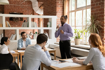 Successful African American male team leader hold microphone talk with multiracial employees in...