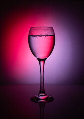 silhouette of transparent glass of whater  on red and purple background