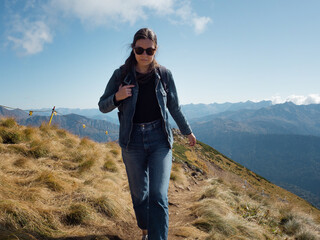 Hiking in the mountains, a young female tourist with a backpack is walking along