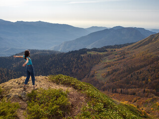 Fototapeta premium tourist stands on top of a mountain with her arms outstretched, Hiking in the mountains.