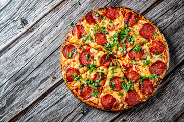 Pepperoni Pizza with Mozzarella cheese, salami, Tomato sauce, pepper, Spices and Fresh basil. Italian pizza on wooden table background