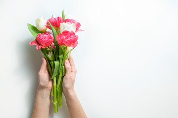 Cropped shot of woman's hands holding a bunch of tulips over white background. Female composing a bouquet. International Women's day greeting concept. Copy space, close up, top view, flat lay.