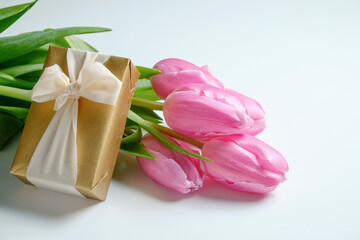 A bouquet of pink french single late tulips and golden gift box. Tender minimalistic spring flowers composition isolated on white background. Close up, copy space, top view, flat lay, studio shot.