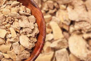 Ginger background. Ginger pieces in wooden bowl. Indian spice texture. Empty copy space cooking background. Ginger root texture.