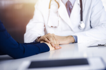 Fototapeta premium Unknown man-doctor reassuring his female patient, close-up. Perfect medical service, empathy in medicine during Coronavirus pandemic