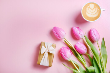 Multipurpose fresh flower composition, bouquet of pink tulips and a present wrapped in golden paper. International Women's day greeting concept. Copy space, close up, top view, flat lay, background.