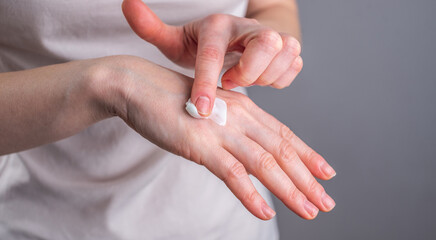 Woman is smearing her hands with cream. Concept of skin care and choice of natural organic cosmetics. Closeup