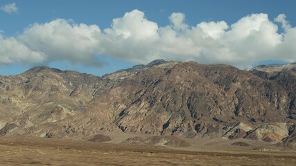 Road trip to Death Valley, Artists Palette drive, California USA. Hitchhiking auto traveling in America. Highway, colorful bare mountains and arid climate wilderness. View from car. Journey to Nevada.