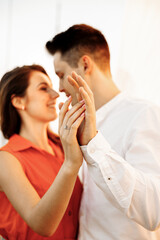 Tender hugs of a young couple in love, hands in the foreground, blurred background.