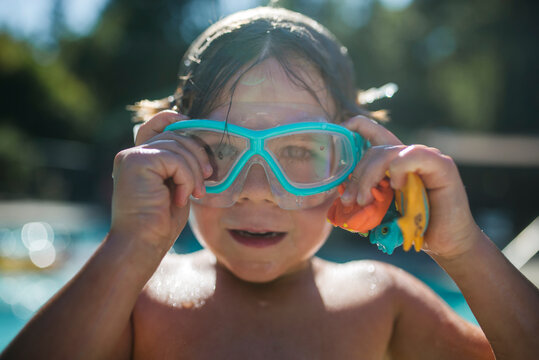 Portrait of shirtless boy adjusting swimming goggles at poolside