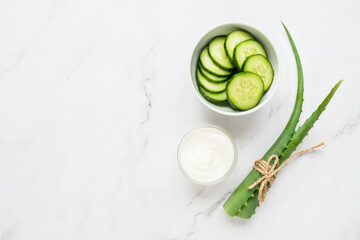 Homemade skin care concept. Green natural ingredients aloe vera, yogurt, cucumber for making a cosmetic mask on a light background.