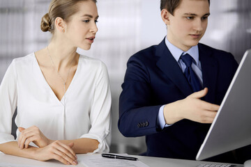 Business people discussing something while sitting in office. Focus at businesswoman while talking to her male colleague. Teamwork and meeting concept