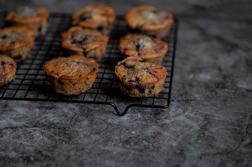 Blaubeer-Muffins auf einem Rost vor Beton Optik Untergrund Detailansicht