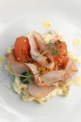 Vegetable salad with ham, parsley and tomato. Restaurant dish on a white plate close-up.