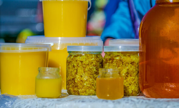 Bee honey and zabrus, packed in jars of different sizes, stand on the table and are ready for sale 