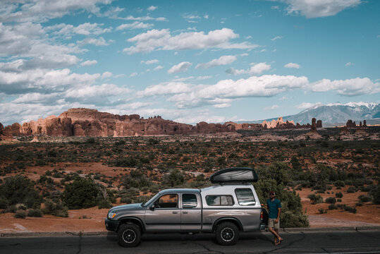 Hiker standing by car on road at Arches National Park