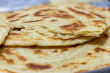 Fresh pita breads. Piece of bread is broken into two pieces. Selective focus.