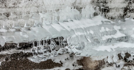 Icicles and frost on a snow-covered frozen river
