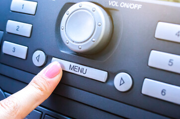 Woman is pressing menu button in the car.