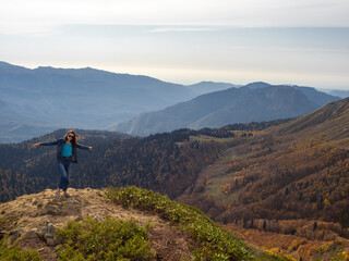 tourist stands on top of a mountain with her arms outstretched, Hiking in the mountains.