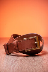Leather brown belt twisted in a sign of infinity on a wooden orange background. High quality photo