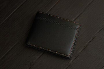Fashionable black leather men's wallet on top of wooden table