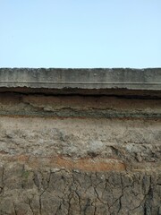 Different colored soil layers have cracks under the concrete road. Caused by geological changes ...