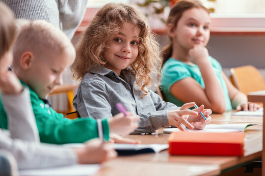 Children sit at the tables in the classroom waiting for the first lesson in the new school year