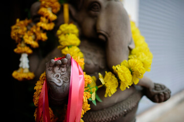 Close-up of Om sign on hand of Ganesha statue with floral garland