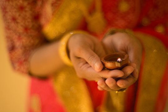 Midsection of woman in sari holding diya during Diwali