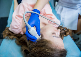 Doctor using ultrasound scanning machine for examining a head of woman