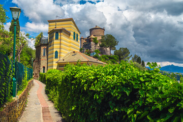 Fototapeta na wymiar Cozy narrow street with green plants and old buildings, Italy