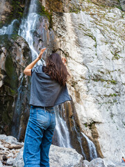 Beautiful and high waterfall. A young woman hikes in the mountains.