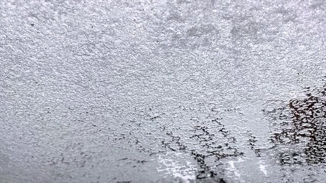 Cockpit view. Ice melts on the windshield of the car. 4K resolution.