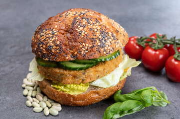 Tasty vegetarian vegan lunch with hamburger made from vegetables based burger, organic bun with seeds and fresh vegetables and french fried potatoes