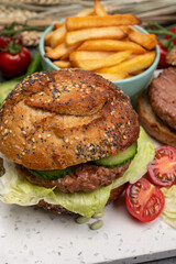 Tasty vegetarian vegan lunch with hamburger made from plant based soya beans burger, organic bun with seeds and fresh vegetables and french fried potatoes