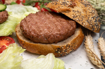 Making tasty vegetarian vegan hamburger from plant based soya beans burger, organic bun with seeds and fresh vegetables