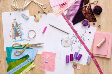Fashion designer workplace with sketches on wooden background