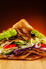 Kebab - grilled meat, bread and vegetables against orange gradient background
