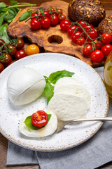 Cheese collection, eating. of white soft Italian cheese mozzarella, served with red cherry tomatoes, fresh basil leaves