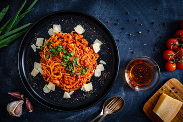 Spaghetti bolognese with minced pork meat and parmesan on black table